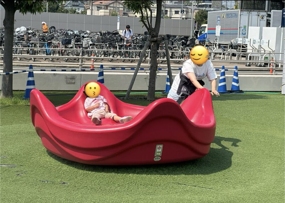 回転遊具で遊ぶ娘と母